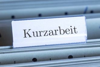 (photo montage) Sign with the inscription KURZARBEIT on a hanging file register