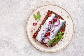 Sandwiches, Herring fish, on dark rye bread, sprinkled with onion, chili pepper and herbs, on a