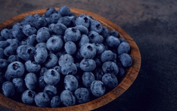 Fresh blueberries, in a wooden bowl, on the table, top view, close-up, no people