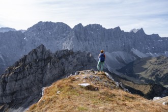 Hiker stands on a rock and looks at Laliederer Wand, hiking to Gamsjoch, down the Ahornboden