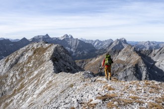 Hikers on the summit ridge of the Gamsjoch, behind rock faces of the Laliderer Spitze, eastern