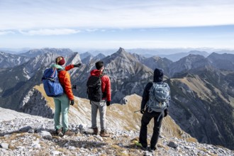 Three hikers on the summit of Gamsjoch look at the mountains, eastern Karwendel, Tyrol, Austria
