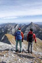 Two hikers on the summit of Gamsjoch look at the mountains, eastern Karwendel, Tyrol, Austria
