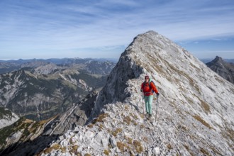 Female hiker on the summit ridge of the Gamsjoch, behind rock faces of the Laliderer Spitze,
