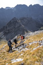 Hikers descending from Gamsjoch, behind dramatic rock faces of the Laliderer Spitze, eastern