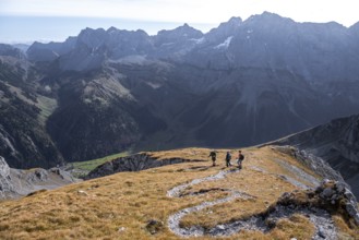 Three hikers descending, hiking trail with serpentines from Gamsjoch, dramatic rock faces of