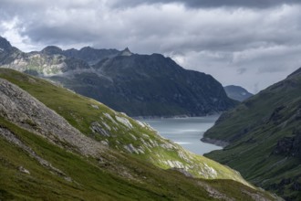 View of a lake in a valley surrounded by mountains, dramatic sky with low-hanging clouds, Lac des