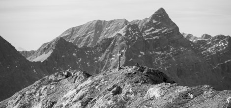 Gamsjoch summit cross in front of dramatic mountain panorama in black and white, Dreizinkenspitze