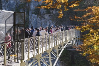 Tourists on Marienbrücke with view of autumnal landscape and rocks, Schwangau near Füssen,