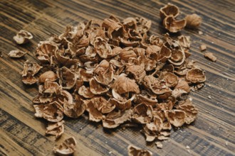 Brown nutshells are scattered on a wooden table, showing remnants of a recent snack. The natural