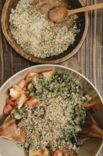 A colorful salad made with fresh tomatoes, cucumber, greens, and a topping of chopped nuts in a