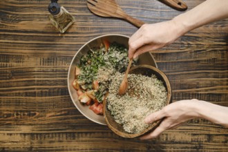 Adding ground walnuts to a bowl with chopped vegetables and herbs. A wooden spoon is used to