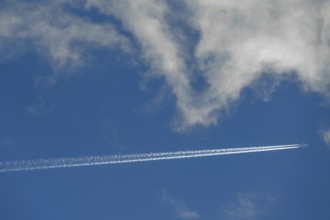 Passenger plane with contrails on a cloudy sky, Bavaria, Germany