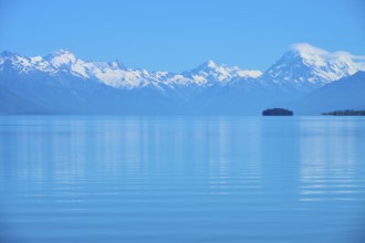Expansive view of a tranquil lake with snow-capped mountains Mount Cook and an island, Lake Pukaki