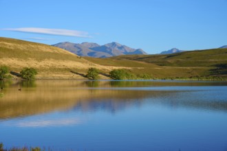 Calm lake with mountains and blue sky in the background, Lake McGregor, Tekapo, Canterbury, South