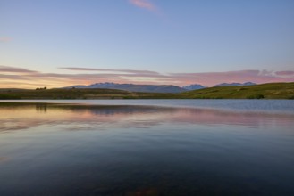 Lake with calm water and mountains in the background with a pink-blue sky, Lake McGregor, Tekapo,