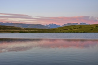 Calm lake with mountains and pink morning sky in the background, Lake McGregor, Tekapo, Canterbury,