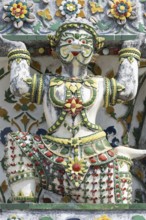 Demon figures (yaksha) supporting the central prang of Wat Arun decorated with colorful ceramic and
