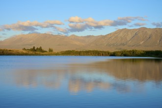 Evening over a calm lake with mountain range and beautiful cloud formation, Lake McGregor, Tekapo,