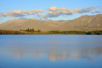 Extensive seascape in evening light with rolling mountains and cloudy skies, Lake McGregor, Tekapo,