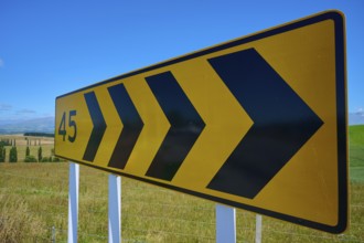 Yellow road sign with black arrows and number 45 on rural road, Geraldine Fairlie Lookout,