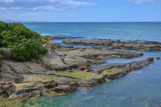 Rocky coastline on the blue sea with cloudy sky and calm water, Shag Point Lookout, Shag Point,