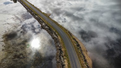 A long bridge over a shallow and calm lake on a cloudy day, photographed with a drone