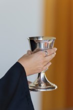 A pastor holds the chalice in both hands to present the drink during Holy Communion in Markt