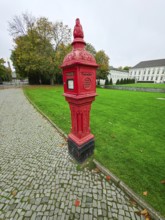 Historic red fire alarm column on cobblestones on the roadside of the Federal President's office,