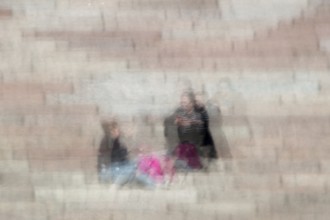 Abstract of a couple sitting on stone steps captured using ICM intentional camera movement