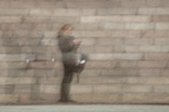 Abstract of a woman looking at the phone in front of stone stairs captured using ICM intentional