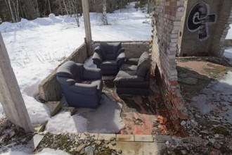 Furniture at burnt hotel frame made of concrete in spring with snow on the ground, Syvälampi,