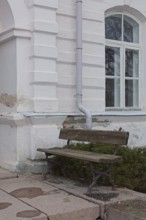 Empty old wooden bench against weathered white stone building, Mustio, Finland