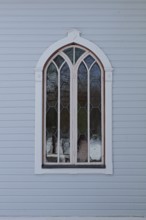 Closed old arched window with white frame on a light blue board wall, Mustio, Finland