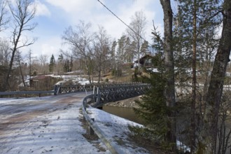 Gravel road on metal bridge over river Mustionjoki in winter, Junkarsborg, Finland