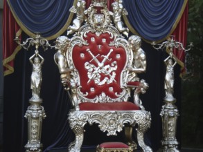 A luxurious royal-style chair with elements such as a crown, lion, angels, and swords, patterns,