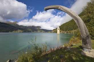 Old Grauner church tower in Lake Resia under a wooden arch in Vinschgau, Italy