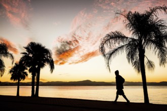 People walking on the sidewalk of Beira Mar Norte Avenue at sunset. Florianopolis, Santa Catarina,