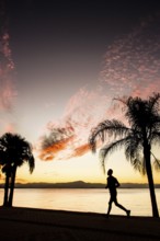 People walking on the sidewalk of Beira Mar Norte Avenue at sunset. Florianopolis, Santa Catarina,