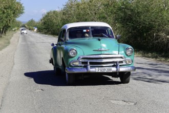 American classic car from the 1950s, near Holguin, Cuba, Vintage green car driving along a rural