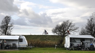 Caravan and motorhome on a campsite, a cyclist drives across the dike on the Baltic Sea, Fehmarn,