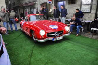 Roter 300 SL rolls across the green carpet through the old town, shiny chrome and rally number,