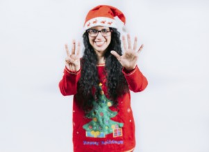 Happy girl in Christmas hat counting number EIGHT, isolated. Smiling girl in Christmas sweater