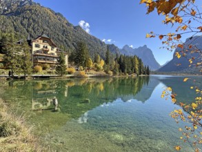 Clear water reflects the surrounding mountains and trees, a house on the shore, Lake Toblach, Lake