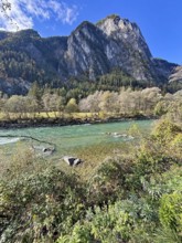 A fast-flowing river in an autumnal mountain landscape, surrounded by trees and rocks, Lienz