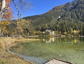 A lakeside villa surrounded by autumnal forests and clear reflection in the water, Lake Toblach,