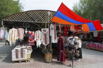 Market stand with traditional clothing and colorful textiles under the Armenian flag, Vernissage
