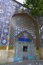 Colourful tiled wall with inscription and traditional pattern surrounds an entrance in a building,
