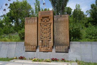 Detailed stone monuments in the open air and surrounded by trees, memorial plaques on Heroes' Alley