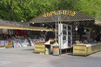 Market square with stalls selling books and souvenirs under a wooden frame outdoors, Vernissage